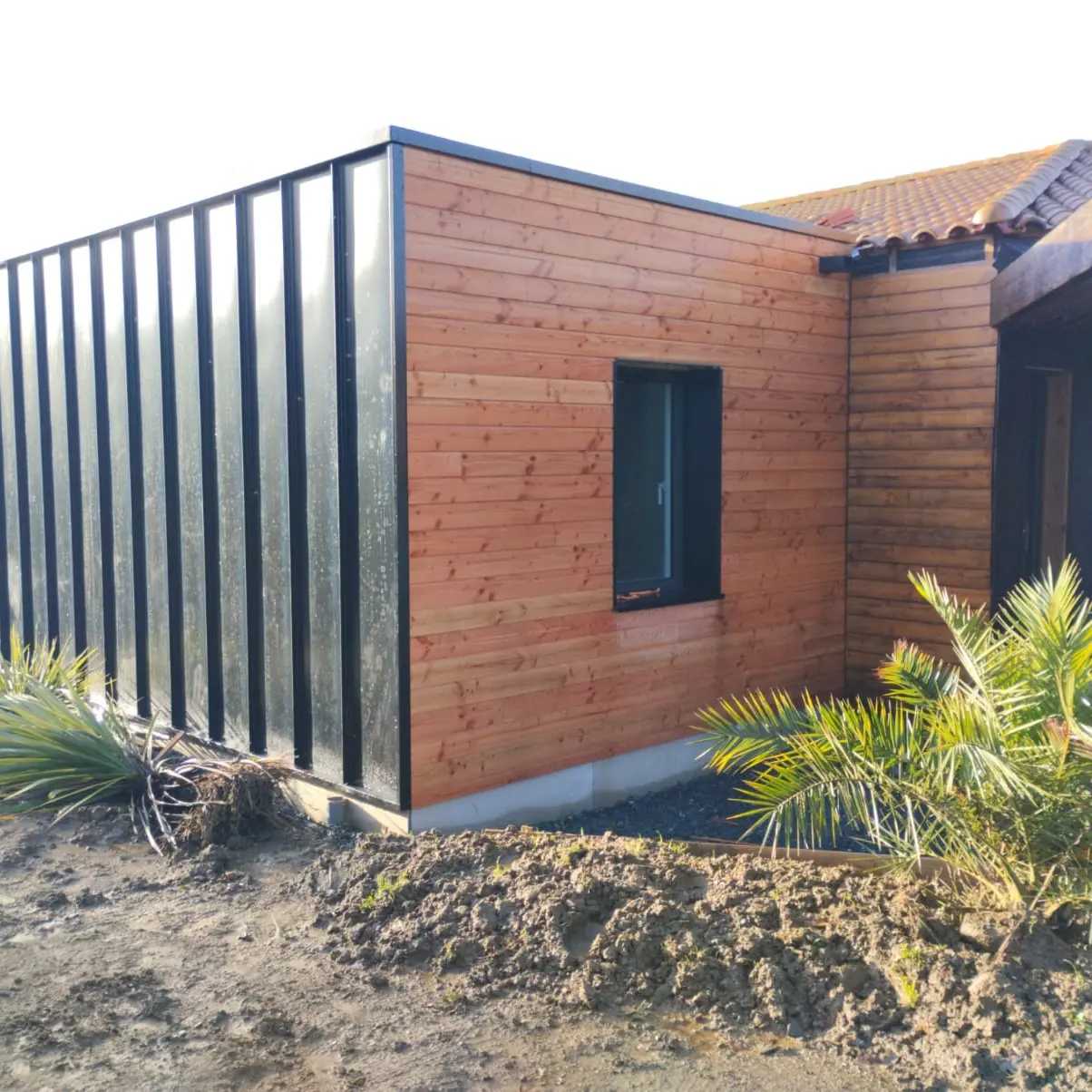 Extension de maison modulaire en bardage imitation zinc et bardage bois.